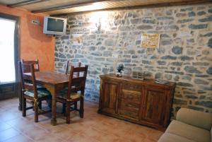 a dining room with a table and chairs and a tv at Apartamento el Patio Casa Cajal in Torla