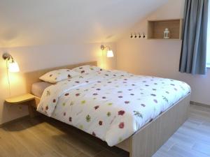 a bed with a white bedspread with flowers on it at Tasteful Holiday Home in Waimes with Sauna in Ovifat