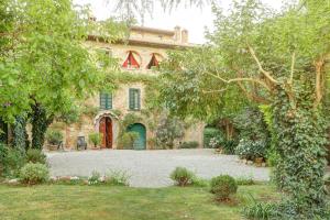 un gran edificio de piedra con un patio con árboles en Le Stanze di Ebe en Lucignano