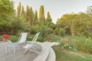 two white chairs sitting on a wooden deck in a garden at Le Stanze di Ebe in Lucignano