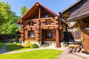 a log cabin building with a porch and a yard at Adelis in Yaremche