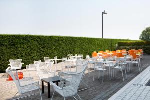 una fila de mesas y sillas blancas con mesas naranjas en Hotel Montemezzi, en Vigasio