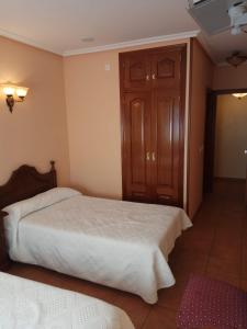 a bedroom with two beds and a wooden cabinet at Hostal Restaurante Raton in Paredes de Nava