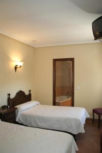 a hotel room with two beds and a bath tub at Hostal Restaurante Raton in Paredes de Nava