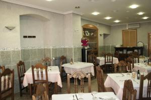 a restaurant with tables and chairs with white tablecloths at Hostal Restaurante Raton in Paredes de Nava
