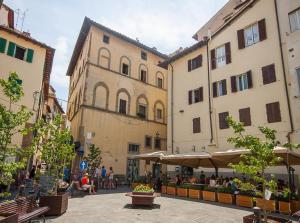 a group of buildings with people sitting in a courtyard at Mamo Florence - Vasari Apartment in Florence