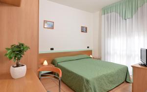 Un dormitorio con una cama verde y una maceta en Hotel Etna, en Lignano Sabbiadoro