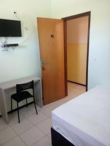 Cette chambre comprend un bureau, une porte et une chaise. dans l'établissement Pousada Cariri, à Juazeiro do Norte