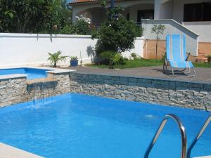a swimming pool with a blue chair next to a stone wall at Attractive holiday home in Vabriga in Vabriga