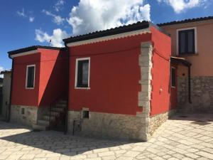 ein rotes Haus mit einer Steinmauer in der Unterkunft La Torre dell'Orologio 2.0 in Roccasicura