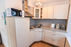 a small kitchen with white cabinets and a microwave at Nida Lotmiskio Apartamentas in Nida