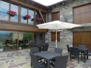 een patio met een tafel en stoelen en een parasol bij Apartaments El Tossalet in Bonansa