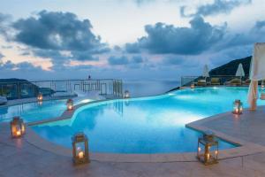 une grande piscine éclairée et offrant une vue sur l'océan dans l'établissement Petani Bay Hotel - Adults Only, à Vóvikes