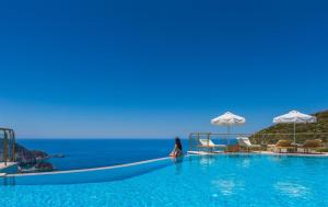 a woman sitting in a pool with the ocean in the background at Petani Bay Hotel - Adults Only in Vóvikes