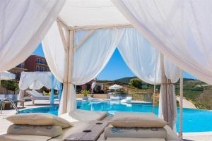 a canopy bed in front of a swimming pool at Petani Bay Hotel - Adults Only in Vóvikes