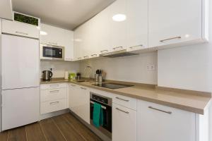 Biała kuchnia z białymi szafkami i urządzeniami w obiekcie weforyou Two Rooms Terramar Alto with Sea View w mieście Benalmádena