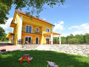 een geel huis met een tuin met twee stoelen bij Luxurious Villa in Tijarica with a Private Pool in Pocrnja