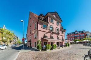 een roze gebouw aan de kant van een straat bij Hotel Goldener Sternen in Konstanz