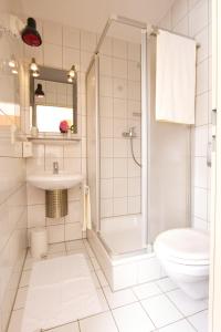 a bathroom with a shower and a toilet and a sink at Hotel Reinhardtshof Garni in Wolfschlugen