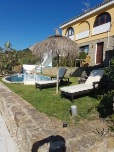 a house with a grass umbrella and a pool at Villa Balcon del Duque in Zahara de los Atunes