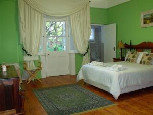 Dormitorio verde con cama y ventana en Bisibee Guest House, en Oudtshoorn