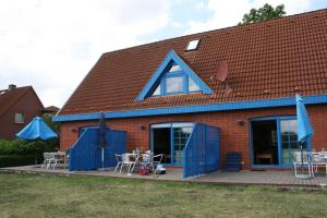ein Haus mit blauen Türen, Tischen und Stühlen in der Unterkunft Zur alten Schmiede I (Mitte) in Boltenhagen
