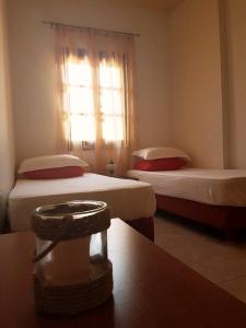 メギスティ島にあるMaria's Apartmentsの窓とテーブル付きのベッド2台が備わる客室です。