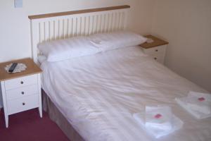 a bedroom with a white bed with two night stands at The Poldark Inn in Delabole