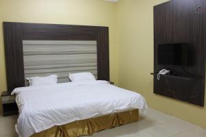 a bedroom with a large bed and a flat screen tv at Rayanat Abha Aparthotel in Abha