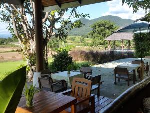 a patio with tables and chairs and a view of a field at Kuad Khon Thoe Pai Cottage in Pai