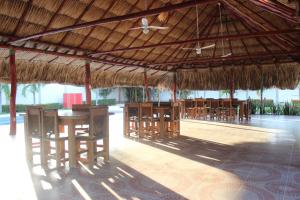 a pavilion with tables and chairs under a straw roof at Hotel Emerawaa in Ríohacha