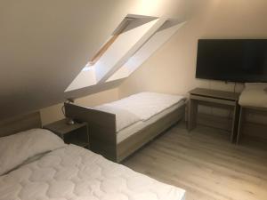 a bedroom with two beds and a skylight and a television at Apartman Gondola in Győr