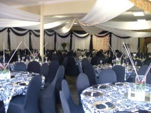 a banquet hall with blue tables and chairs and people at Nigel Goldfields Lodge in Nigel