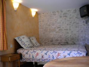 Chambre d'hôte Au col de Cygne في Blanzac-lès-Matha: غرفة نوم بسرير وجدار حجري