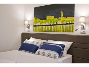 a bedroom with a bed with a painting on the wall at IDRO Studio Apartments directly at the beach in Split