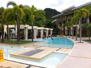 a swimming pool with palm trees in a building at Pico Beach Front Condo in Nasugbu