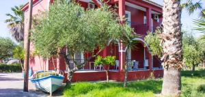 a red building with a boat in front of it at No Name Apartments in Laganas