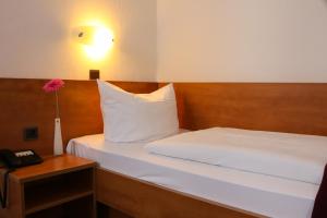 una camera da letto con un letto bianco e un vaso con un fiore di City Hotel Journal a Wolfsburg