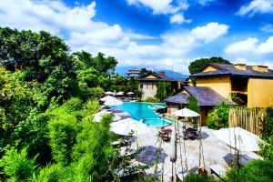 ein Pool mit Sonnenschirmen und ein Resort in der Unterkunft Temple Tree Resort & Spa in Pokhara