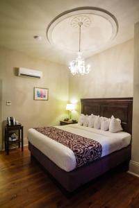 um quarto com uma cama grande e um lustre em Inn on St. Peter, a French Quarter Guest Houses Property em Nova Orleães