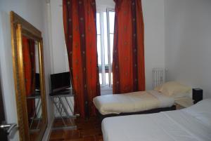 a bedroom with two beds with red curtains and a mirror at Appart Nice Promenade in Nice
