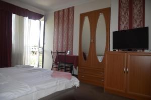 a bedroom with a bed and a dresser with a flat screen tv at Ida Panzió in Budapest