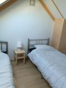 a bedroom with two beds and a table with a lamp at Wenduine zeehuisje 16 in Wenduine