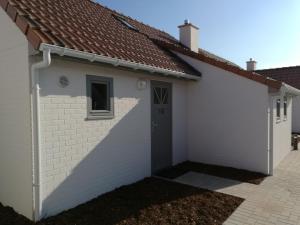eine weiße Garage mit braunem Dach in der Unterkunft Wenduine zeehuisje 16 in Wenduine