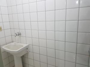 a bathroom with a white tiled wall and a sink at Asa Norte in Brasilia