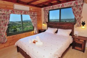 a bedroom with a large bed with two windows at Spa Suites Bemorad Hahar in Even Menahem