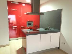 a kitchen with red and white cabinets and a sink at Frente al mar 1ª línea de playa in Conil de la Frontera