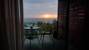 a table and chairs on a balcony with a sunset at Studio Tia in Mamaia