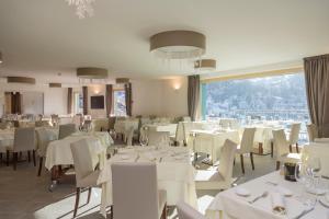 a restaurant with white tables and chairs and a large window at White Angel Hotel in Breuil-Cervinia