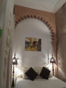 um quarto com uma cama branca e 2 candeeiros em Riad Arous Chamel em Tânger